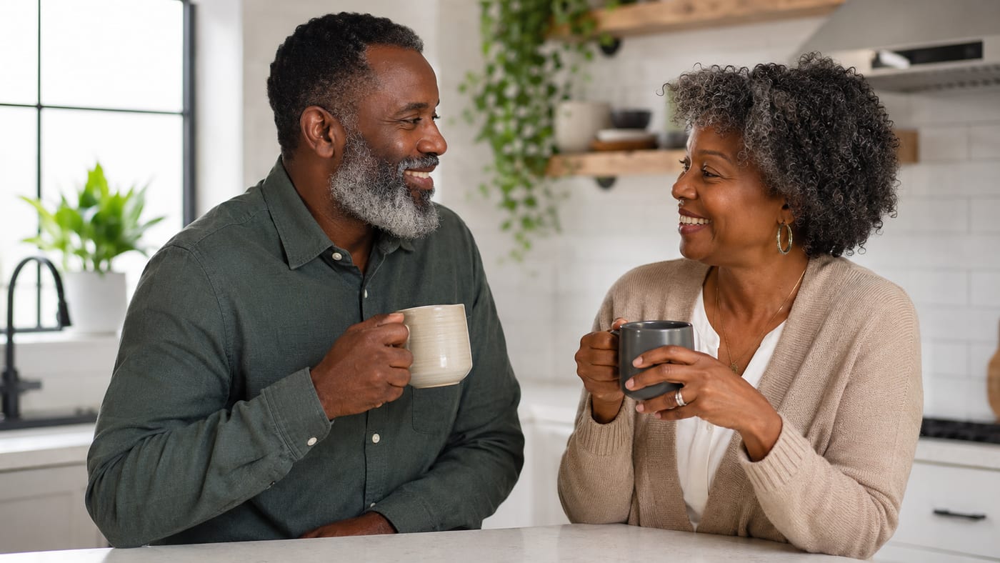 Black man with a well-groomed salt-and-pepper beard smiling in a sunlit kitchen